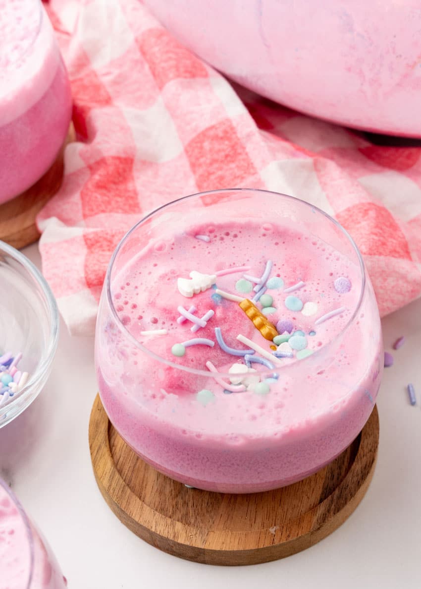 unicorn punch in a small glass on a wooden coaster