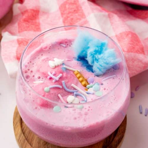 unicorn punch in a small glass on a wooden coaster