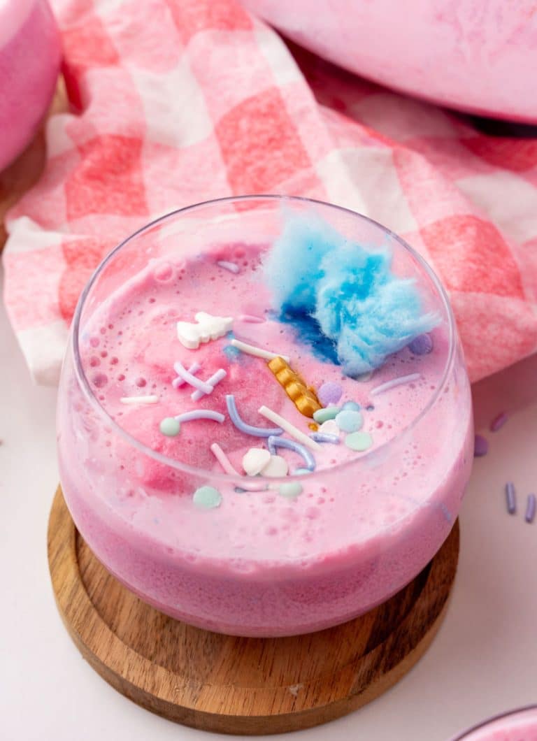 unicorn punch in a small glass on a wooden coaster
