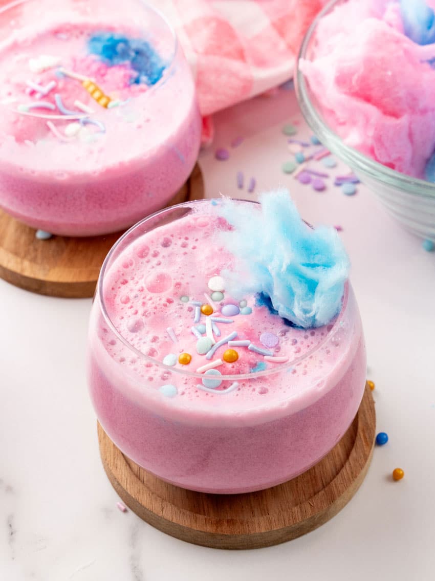 unicorn punch in a small glass on a wooden coaster