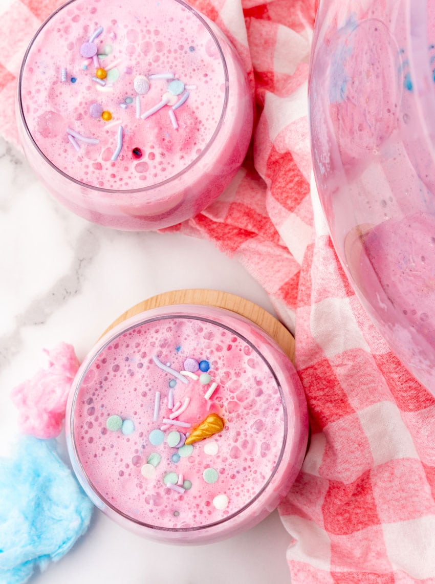 unicorn punch in a small glass on a wooden coaster