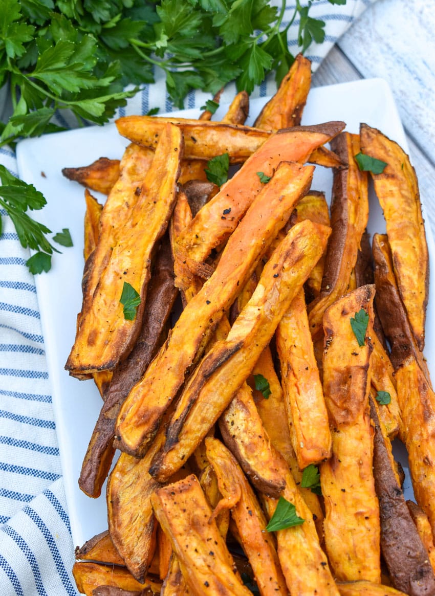 air fryer sweet potato fries piled on a white serving platter