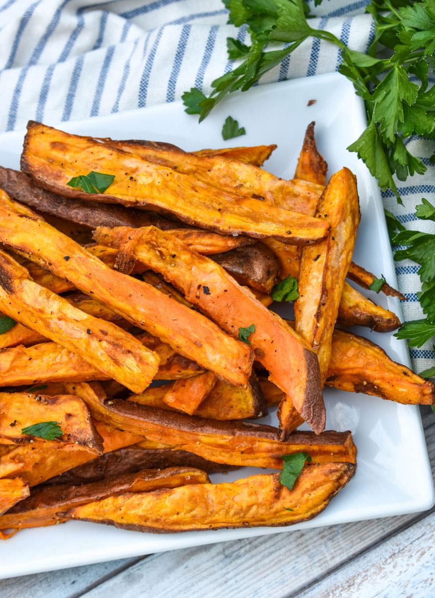 air fryer sweet potato fries piled on a white serving platter
