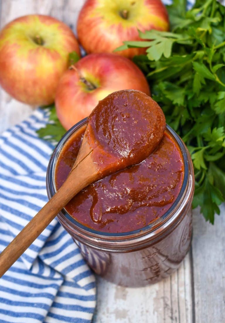 a small wooden spoon scooping homemade apple butter barbecue sauce out of a small glass jar