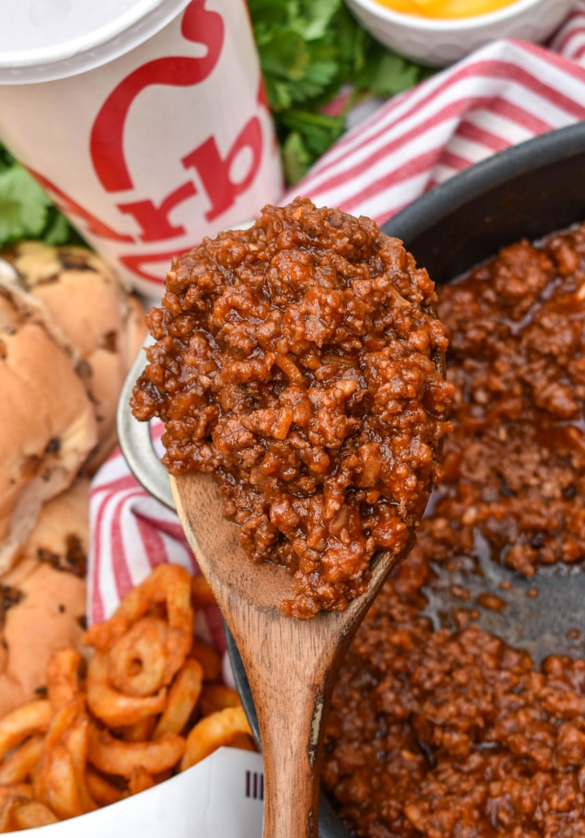 a wooden spoon holding up a scoop of arby's sloppy joe sauce