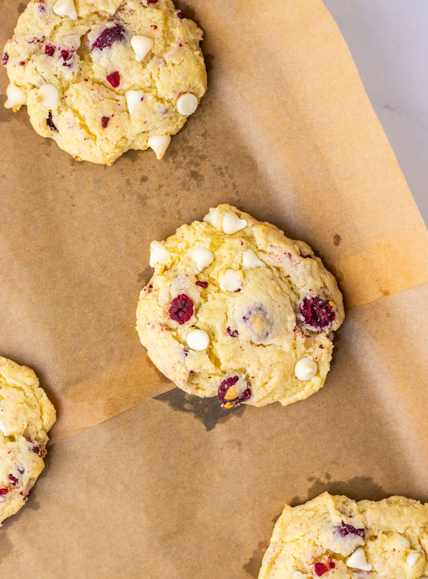 baked raspberry cheesecake cookies on a parchment paper lined baking sheet