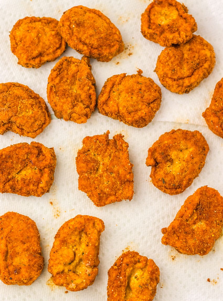 freshly fried spicy chicken nuggets draining on paper towels