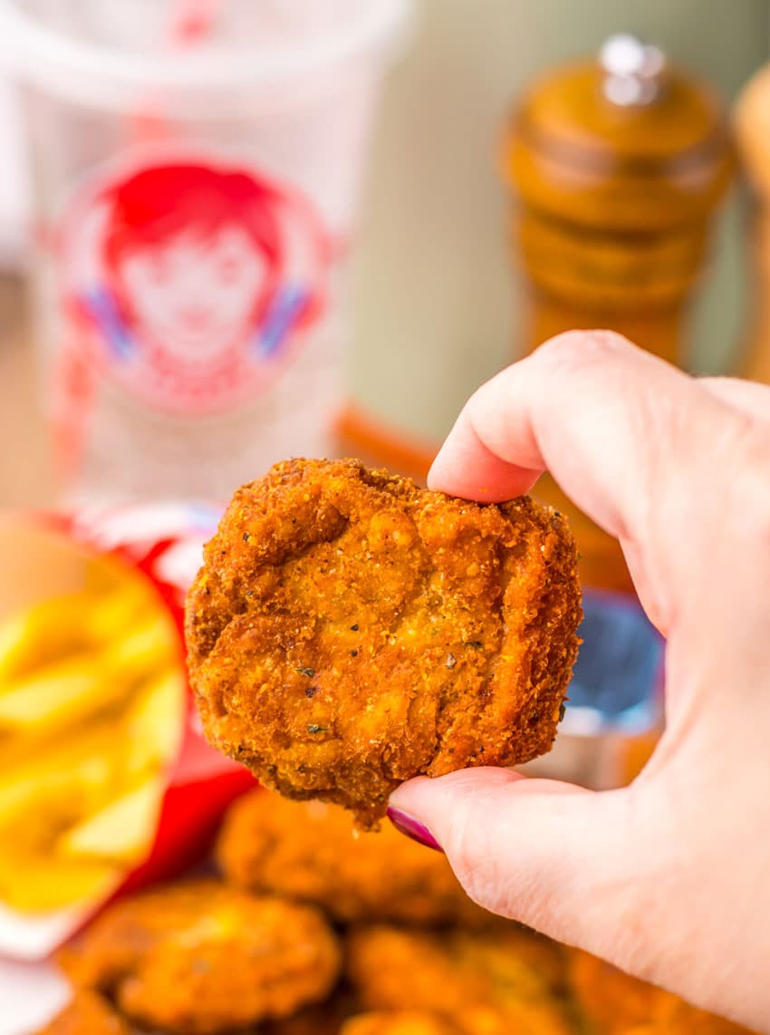 a hand holding up a homemade copycat wendy's spicy chicken nugget