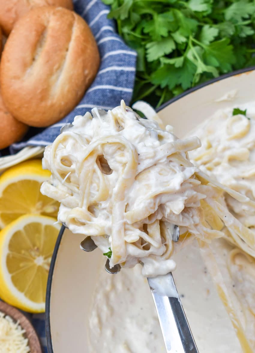 a silver spoon holding up a scoop of creamy crab pasta