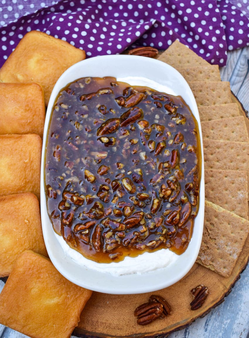 pecan pie dip in a white serving dish surrounded by graham crackers and mini pound cakes