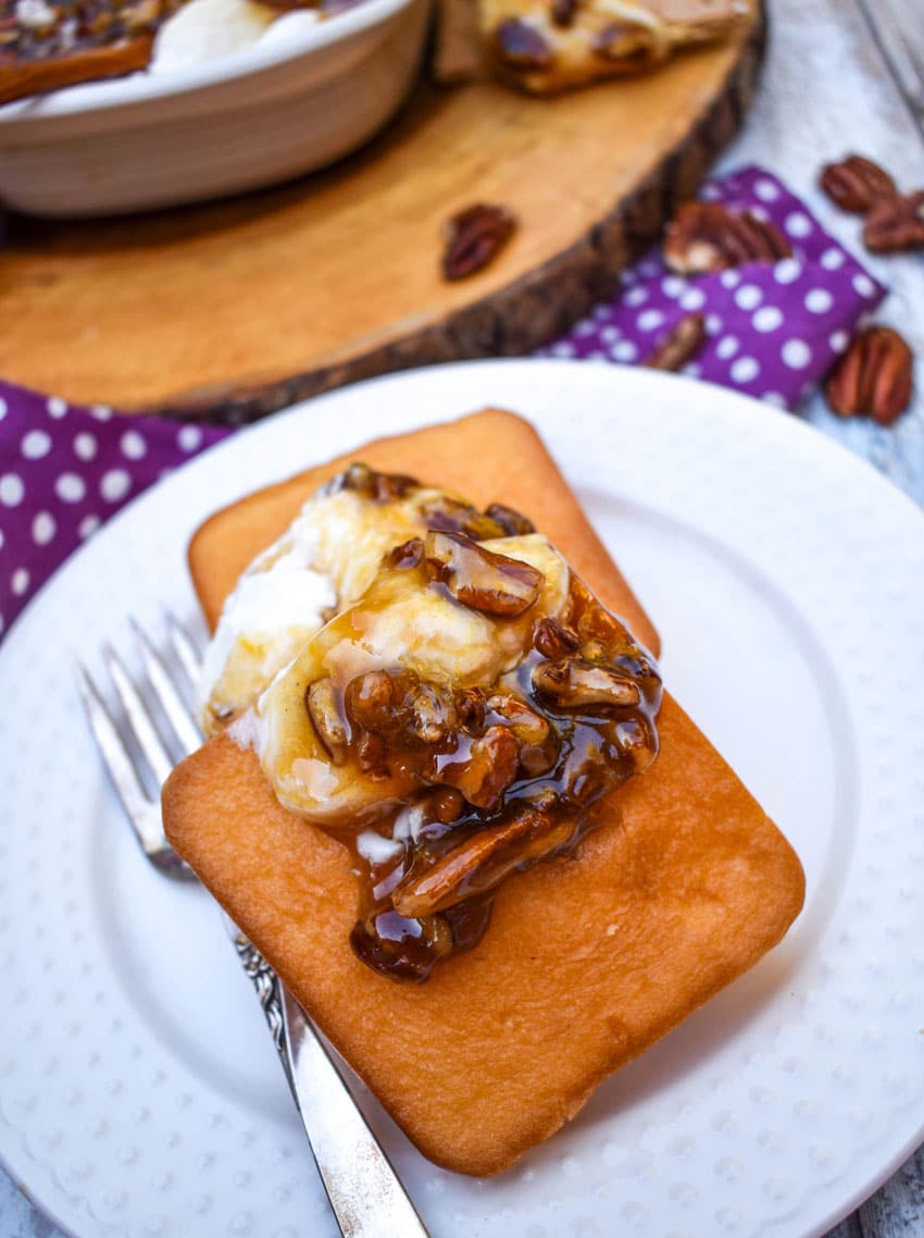 pecan pie dip spooned over two small pound cake squares on a small white dessert dip