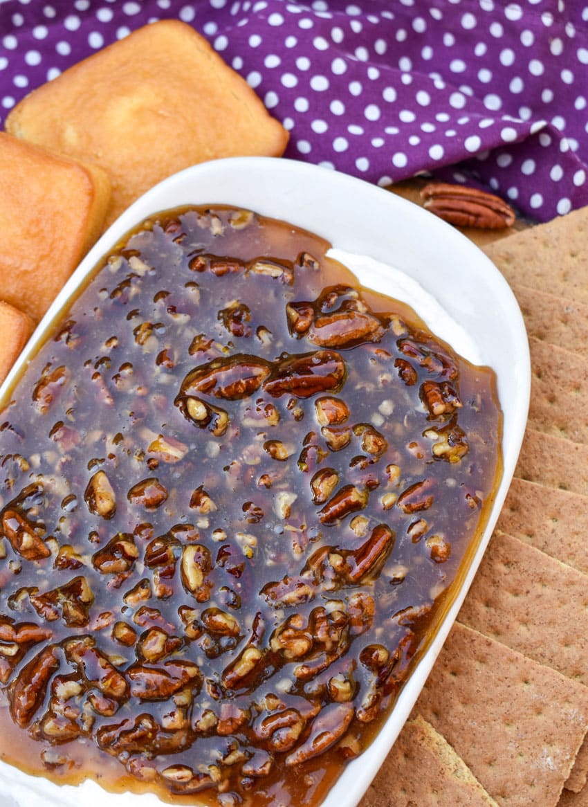 pecan pie dip in a white serving dish surrounded by graham crackers and mini pound cakes