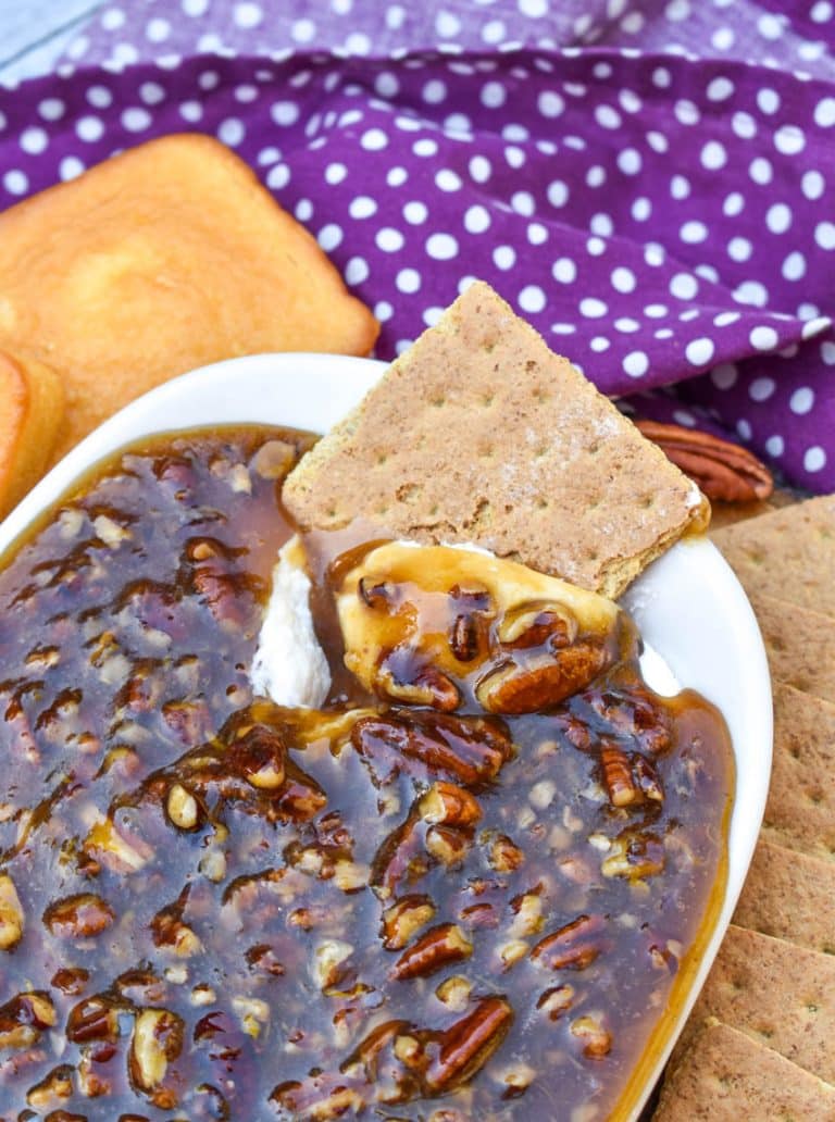 a graham cracker scooping pecan pie dip out of a small white dish