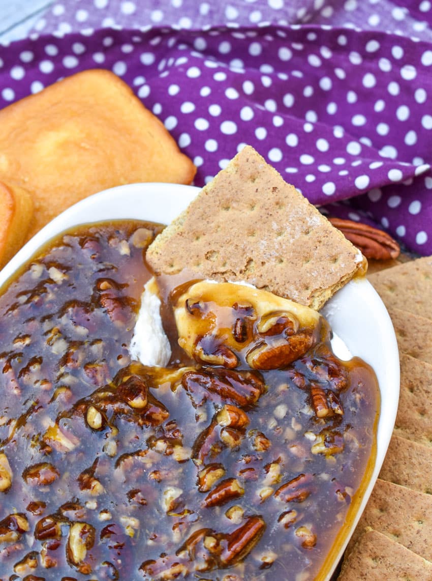 a graham cracker scooping pecan pie dip out of a small white dish