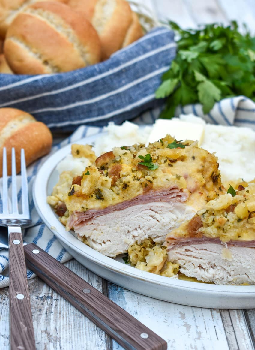 slow cooker chicken cordon bleu next to mashed potatoes and canned green beans on a white plate