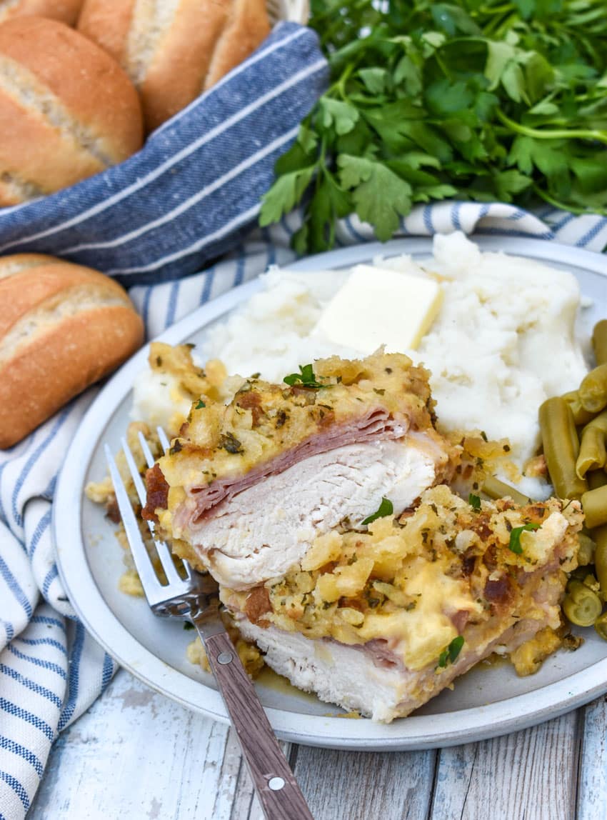 slow cooker chicken cordon bleu next to mashed potatoes and canned green beans on a white plate