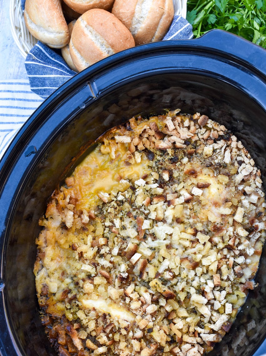stuffing topped layered chicken cordon bleu in the black bowl of a slow cooker