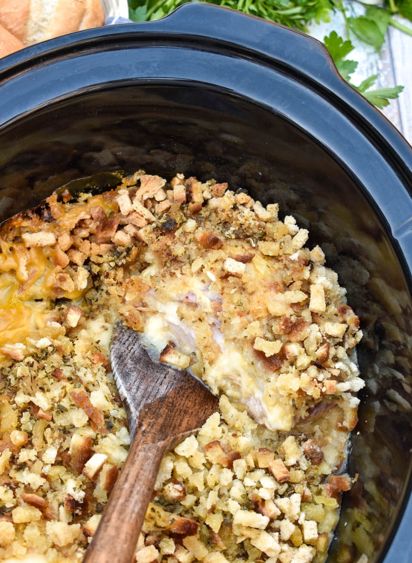 stuffing topped layered chicken cordon bleu in the black bowl of a slow cooker