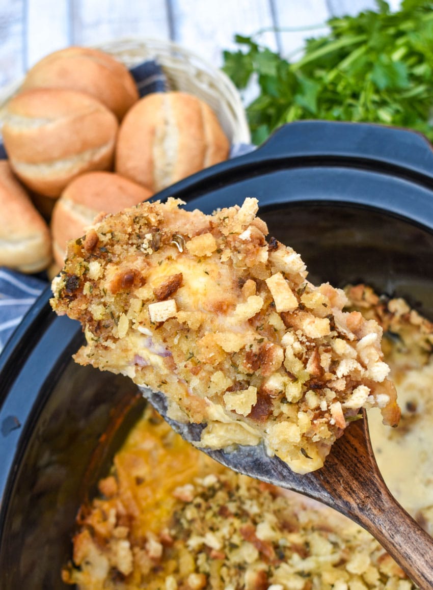 a wooden spatula holding up a piece of slow cooker chicken cordon bleu