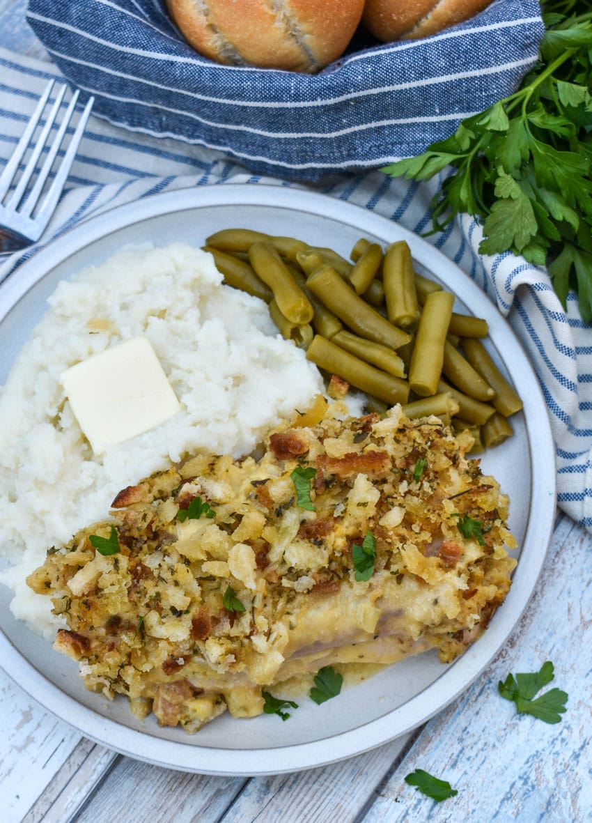 slow cooker chicken cordon bleu next to mashed potatoes and canned green beans on a white plate