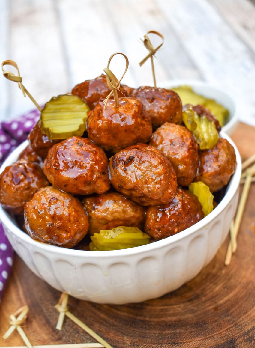 slow cooker hot honey meatballs studded with dill pickle slices piled high in a white serving bowl