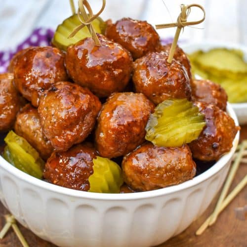 slow cooker hot honey meatballs studded with dill pickle slices piled high in a white serving bowl