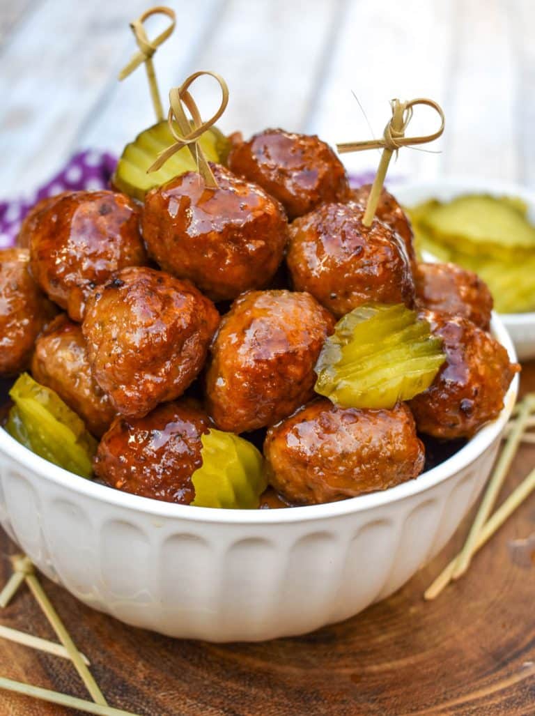 slow cooker hot honey meatballs studded with dill pickle slices piled high in a white serving bowl