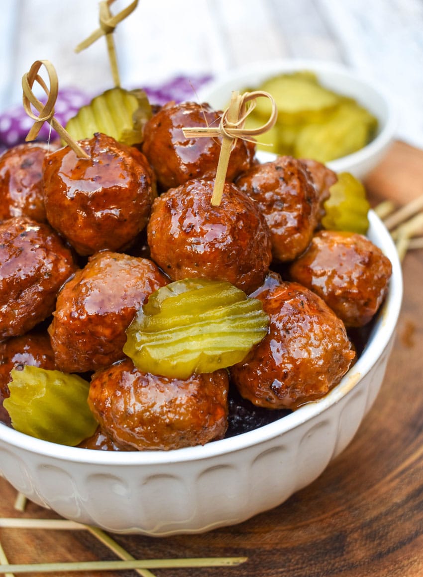 slow cooker hot honey meatballs studded with dill pickle slices piled high in a white serving bowl
