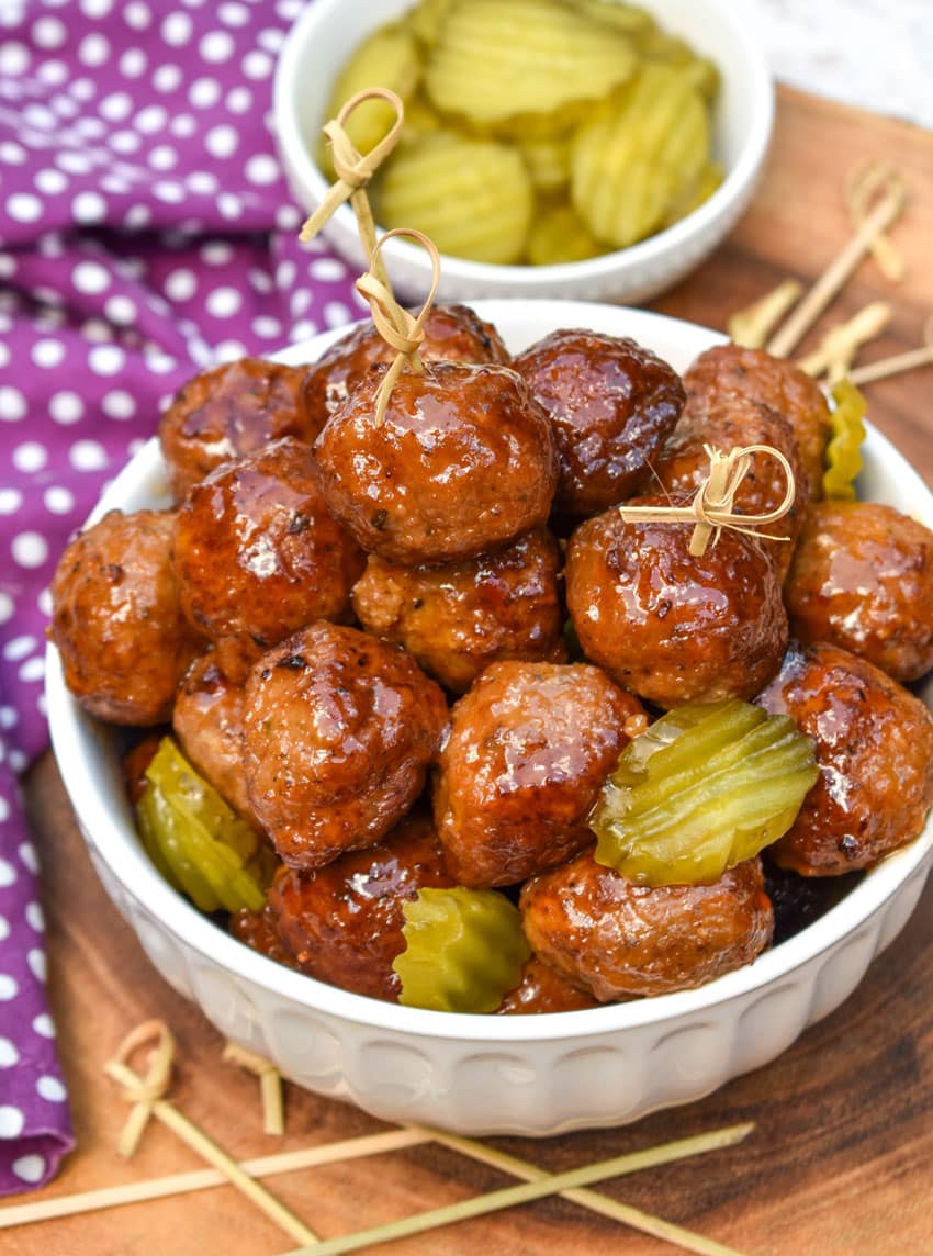 slow cooker hot honey meatballs studded with dill pickle slices piled high in a white serving bowl