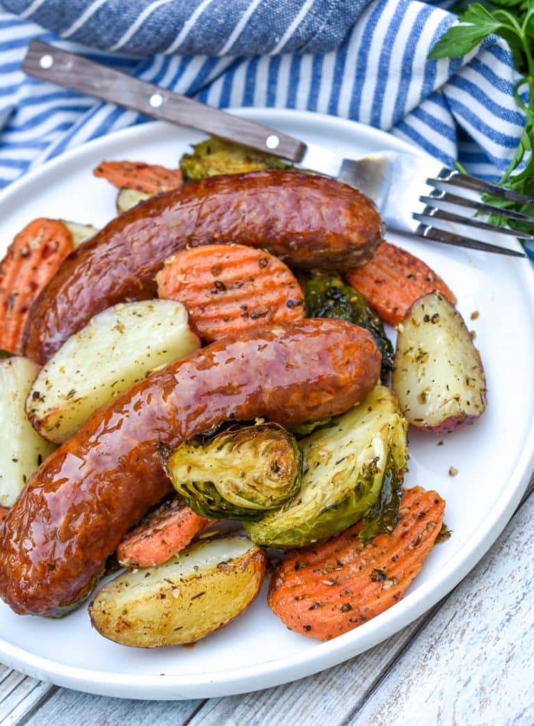 Sheet Pan Sausage and Vegetables on a white plate with a fork resting on the edge