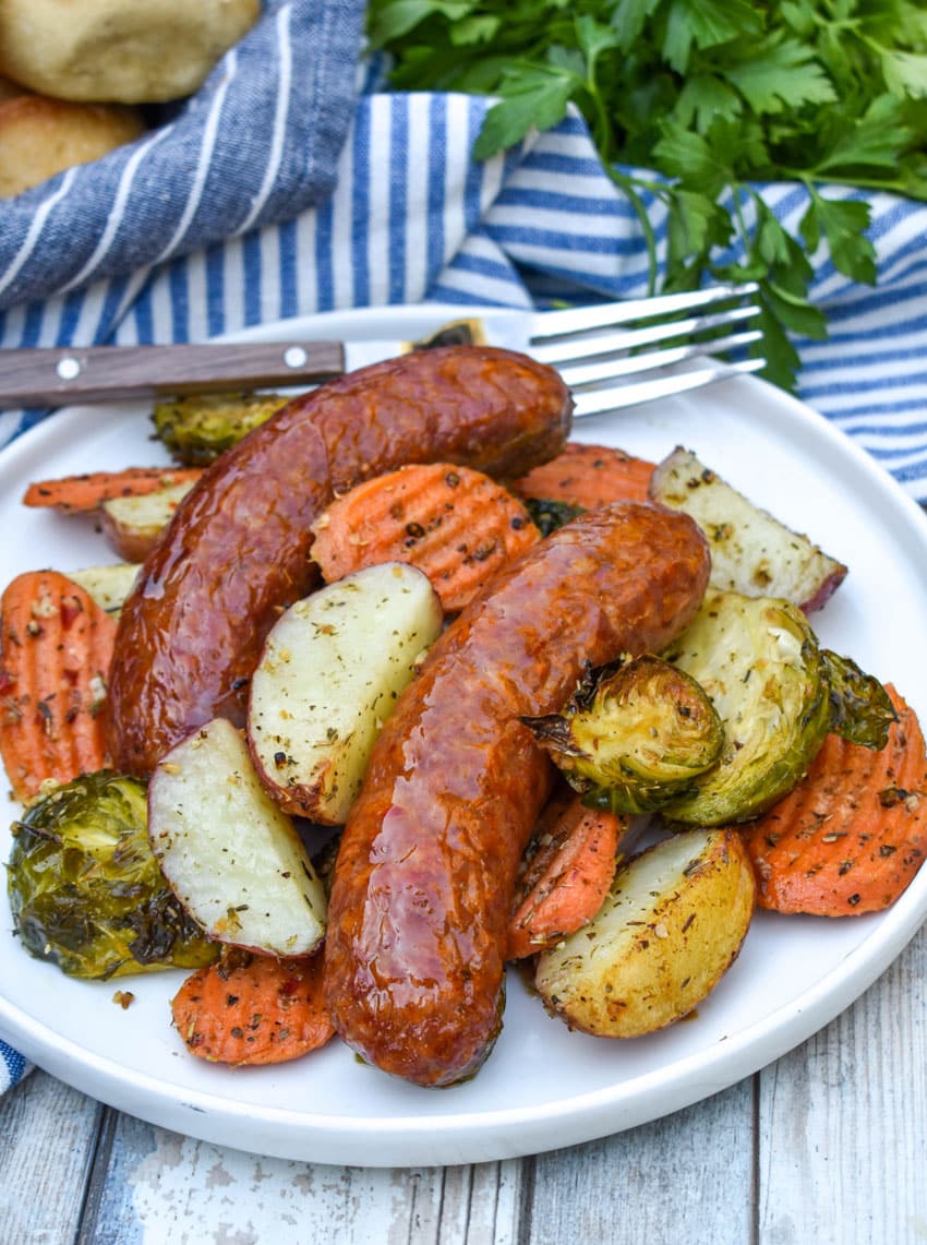 Sheet Pan Sausage and Vegetables on a white plate with a fork resting on the edge