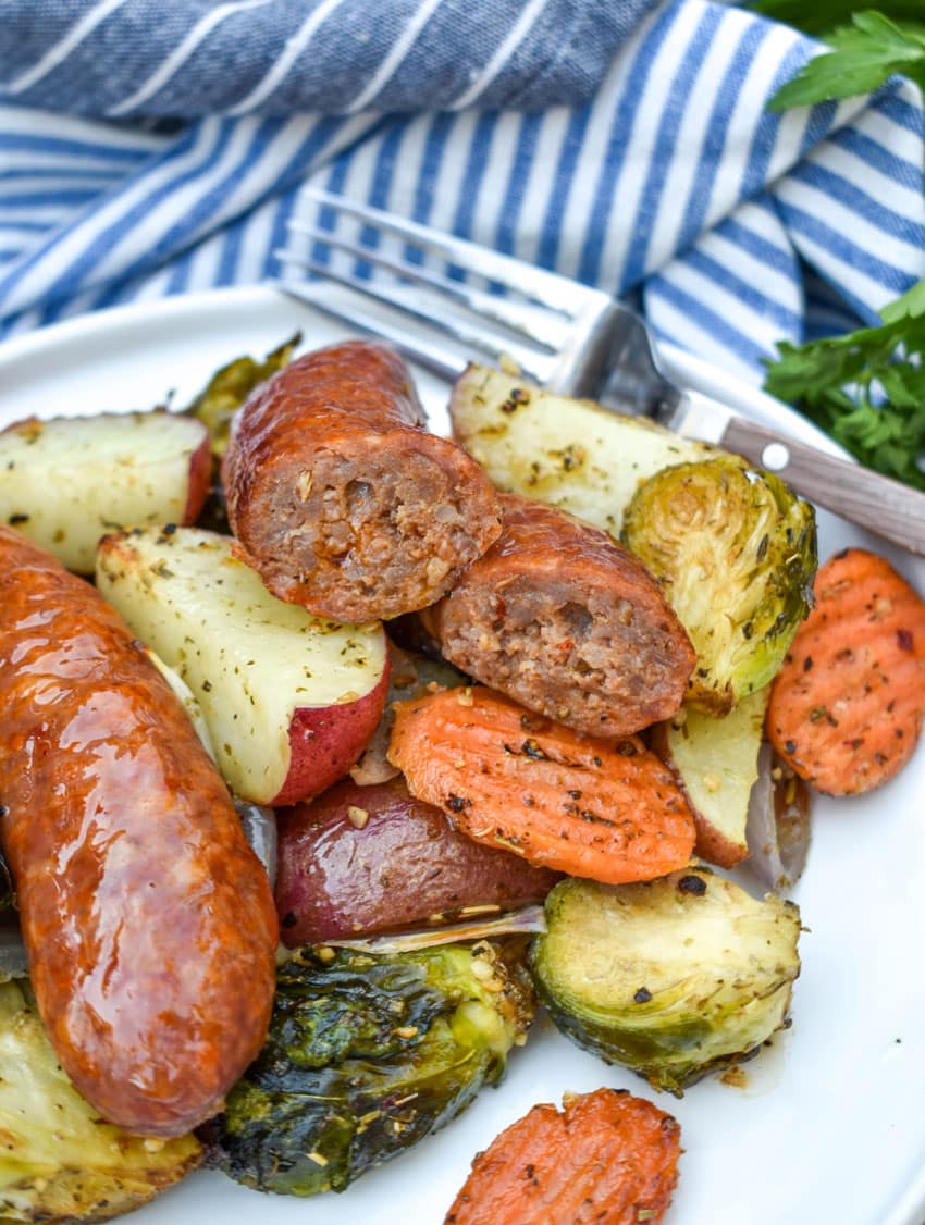 Sheet Pan Sausage and Vegetables on a white plate with a fork resting on the edge