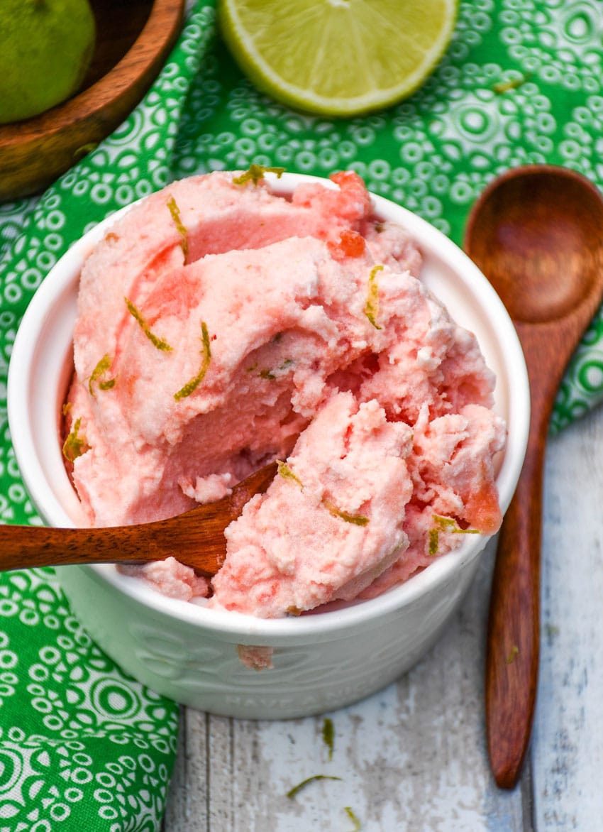 a small wooden spoon scooping 2 ingredient watermelon ice cream out of a small white ramekin