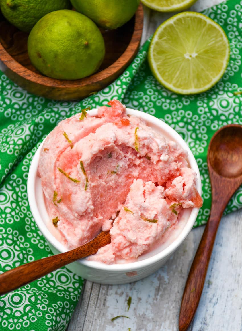 a small wooden spoon scooping 2 ingredient watermelon ice cream out of a small white ramekin