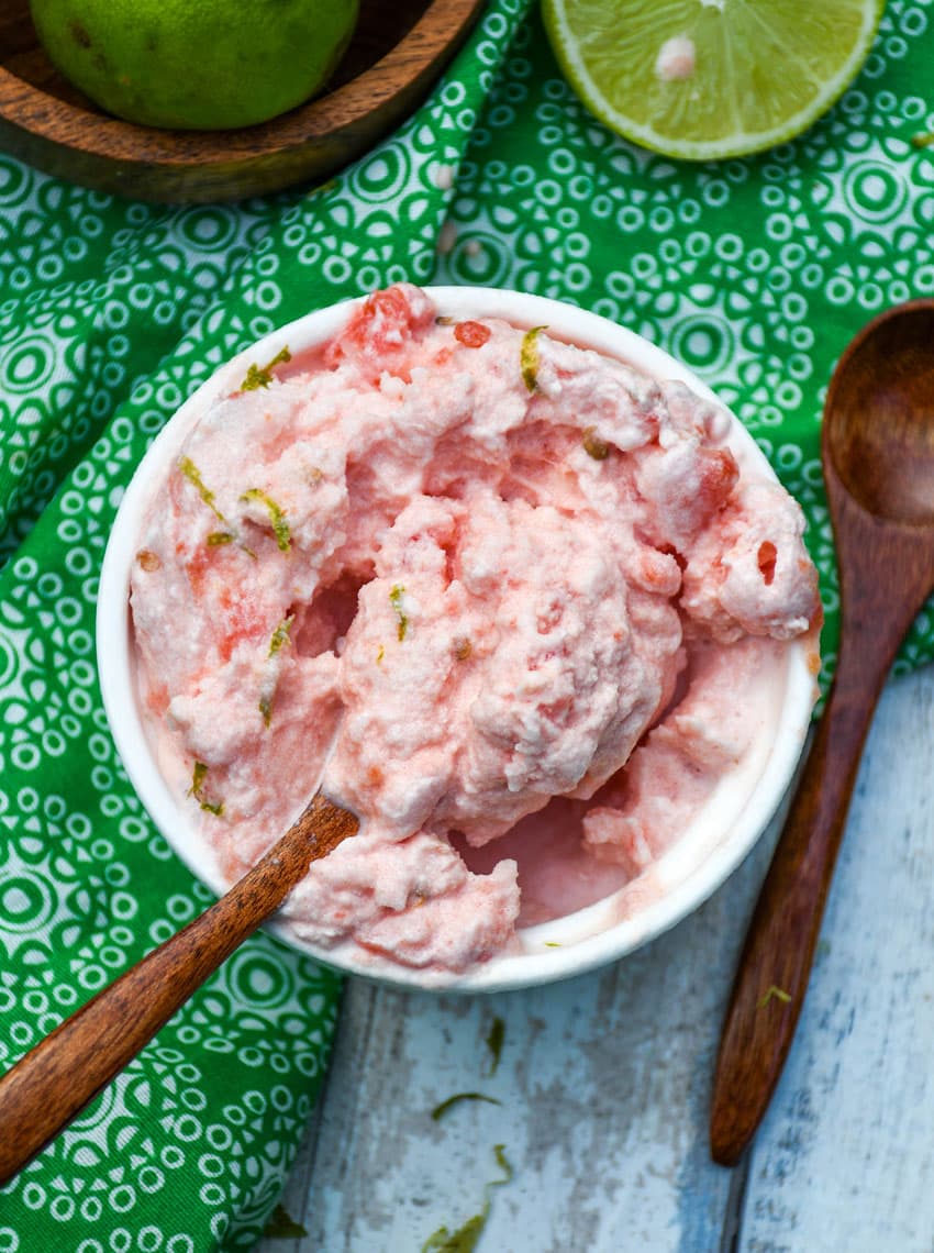 a small wooden spoon scooping 2 ingredient watermelon ice cream out of a small white ramekin
