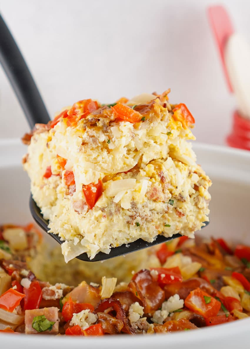 a black spatula holding up a slice of slow cooker breakfast casserole