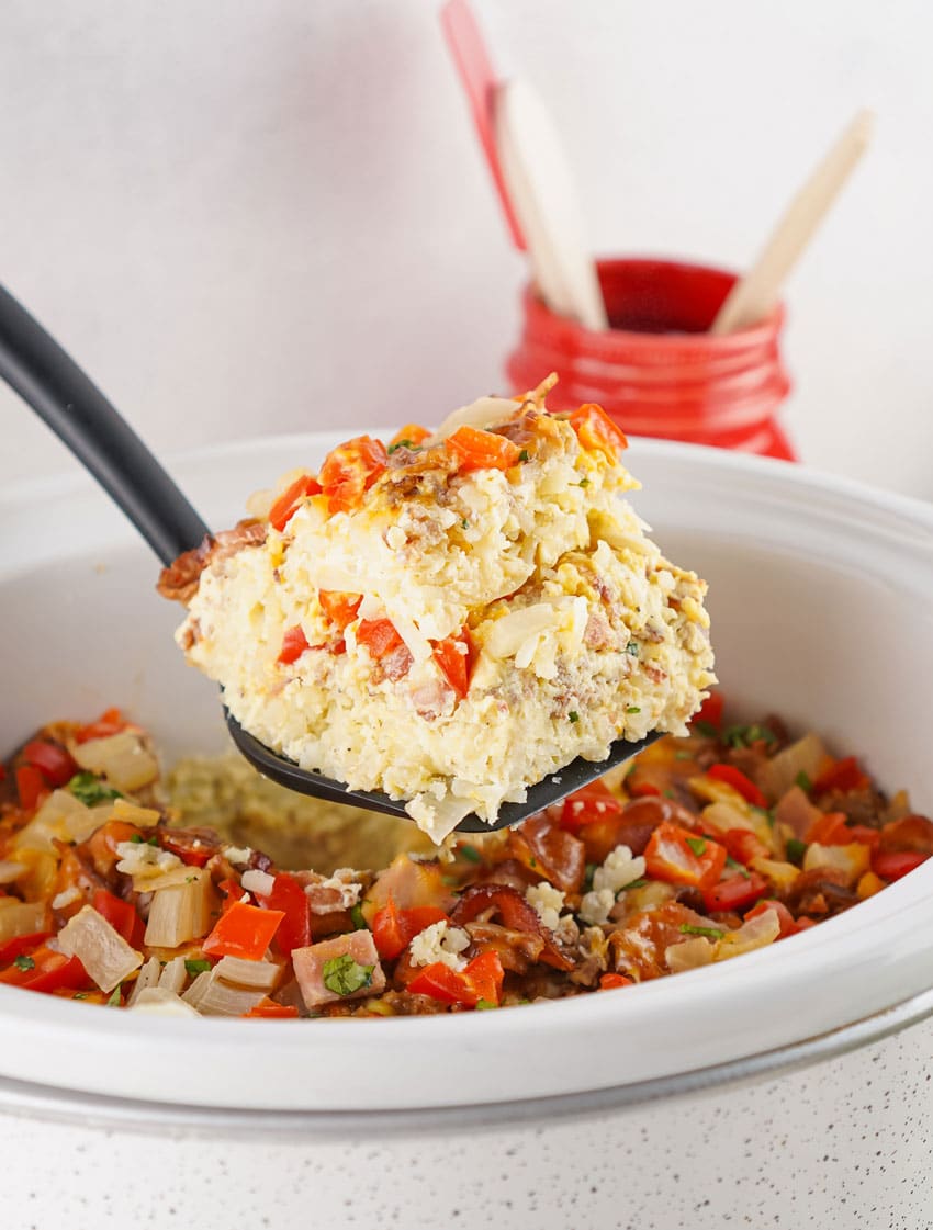 a black spatula holding up a slice of slow cooker breakfast casserole