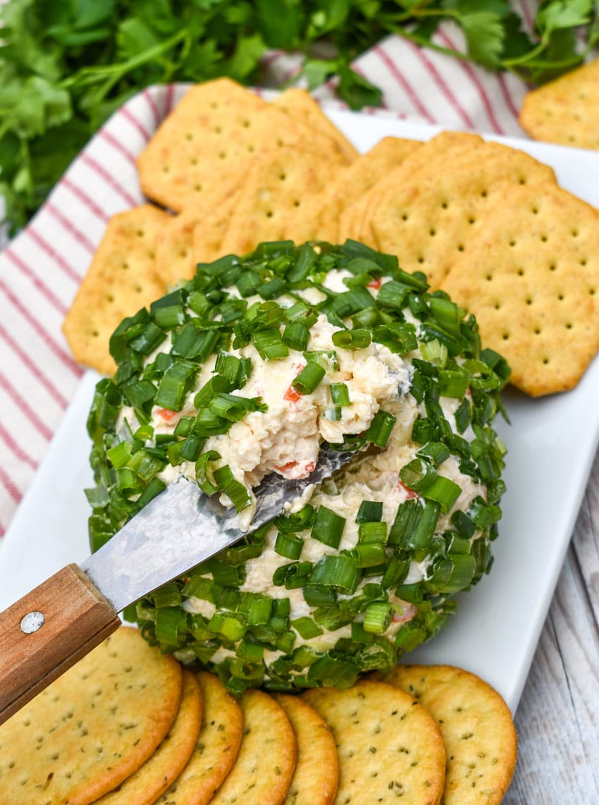 a wood handled cheese serving digging into a crab rangoon cheese ball