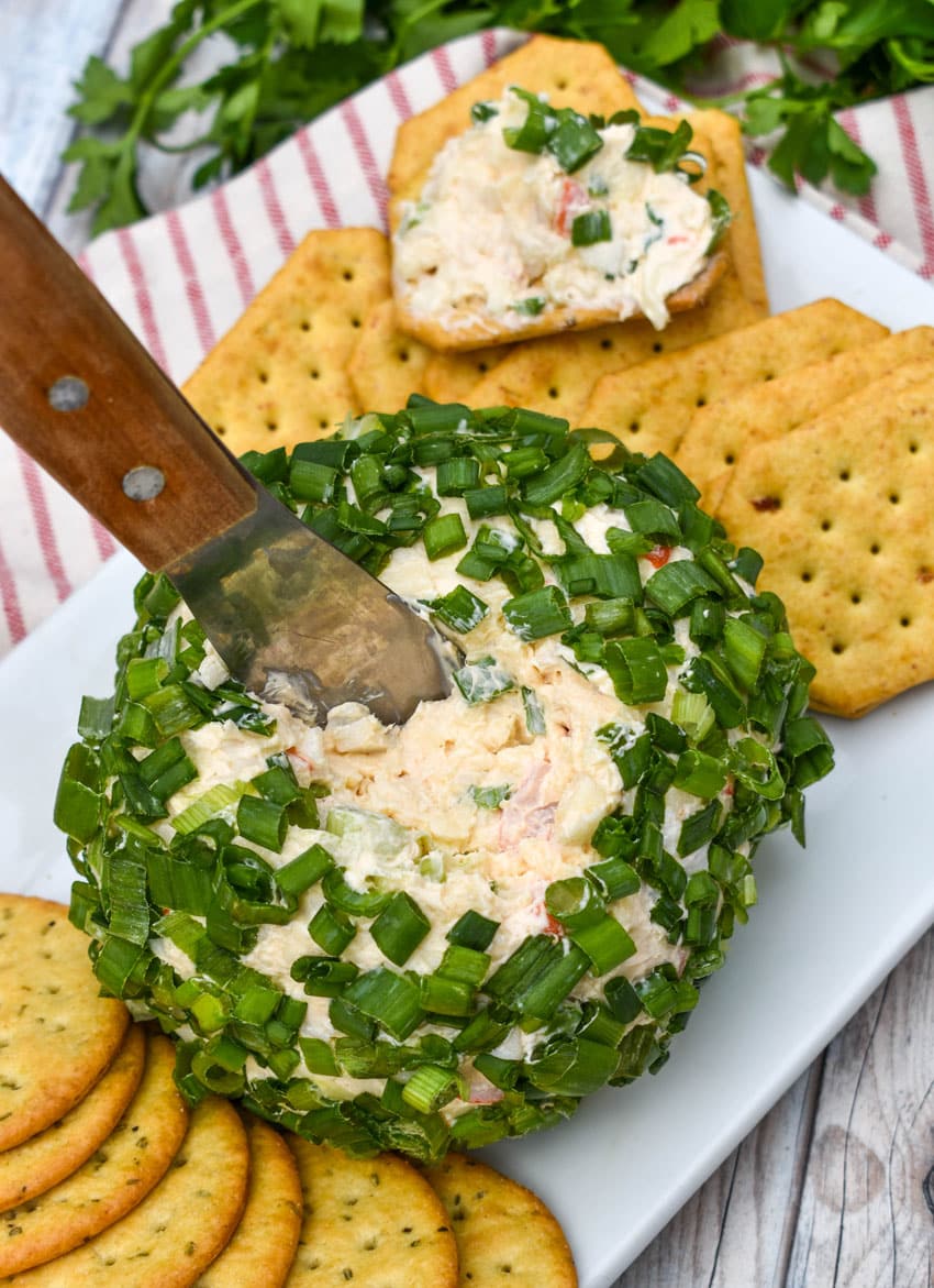 a wood handled cheese serving digging into a crab rangoon cheese ball