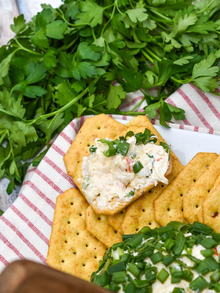 crab rangoon spread on a cracker resting on a white serving platter