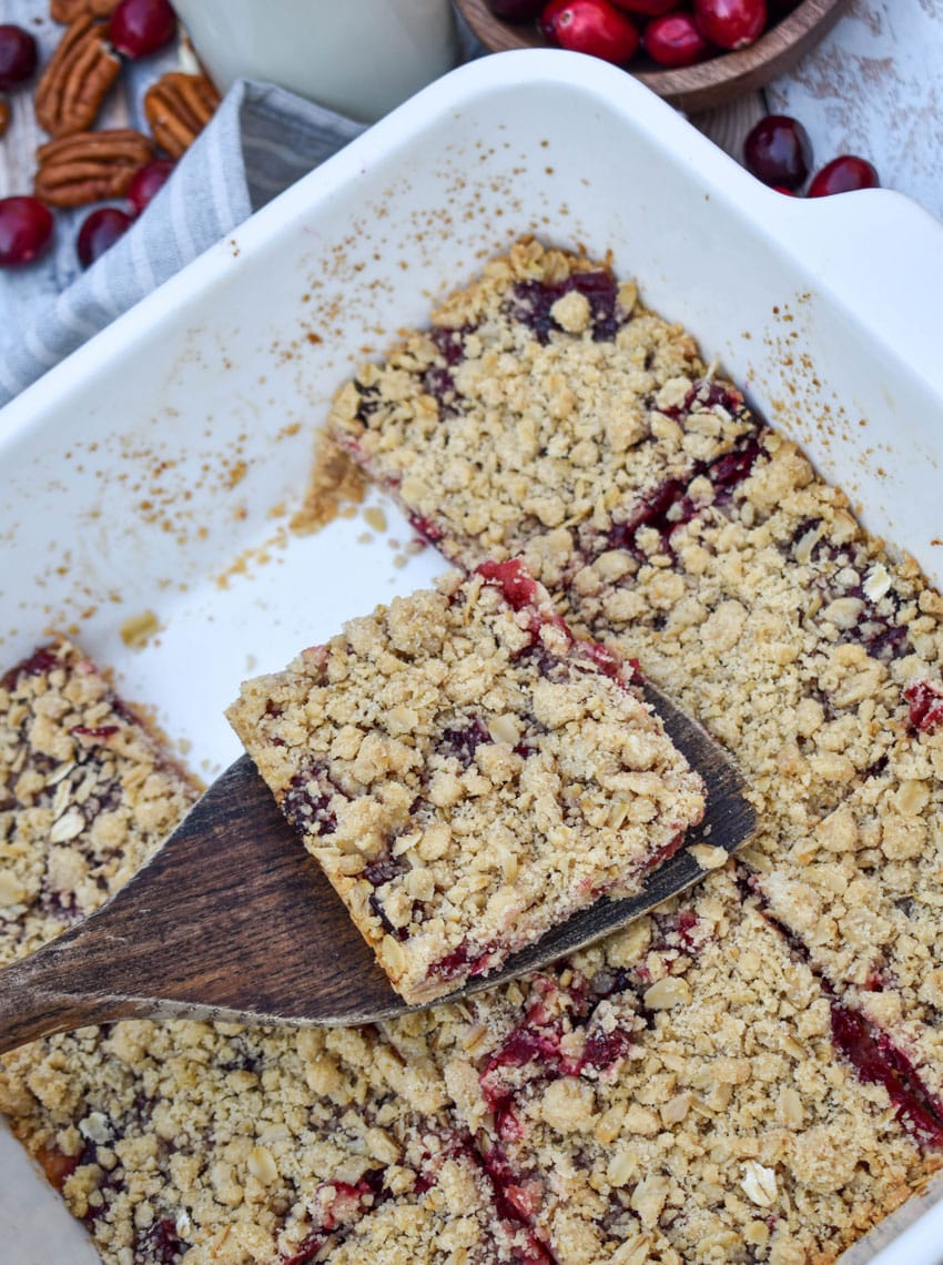 a wooden spatula holding up a sliced cranberry crumble bar