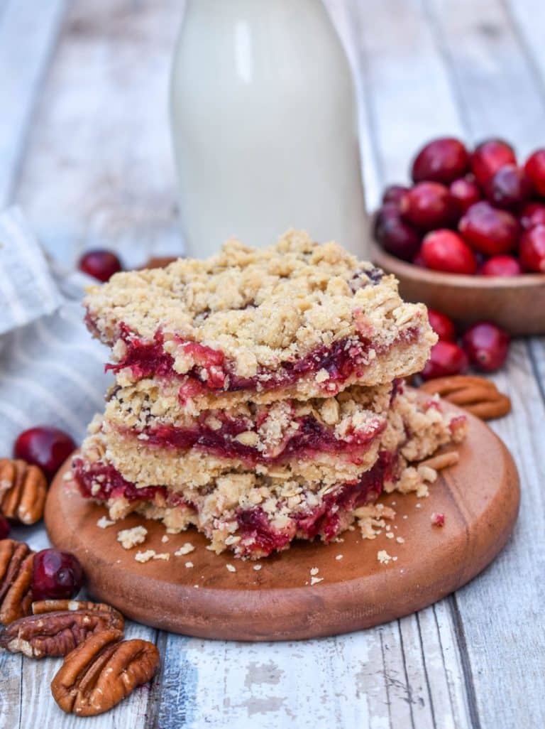 a stack of cranberry crumble bars on a small wooden serving board