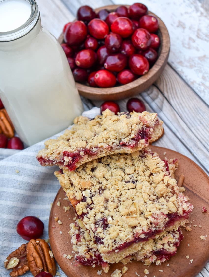 a stack of cranberry crumble bars on a small wooden serving board