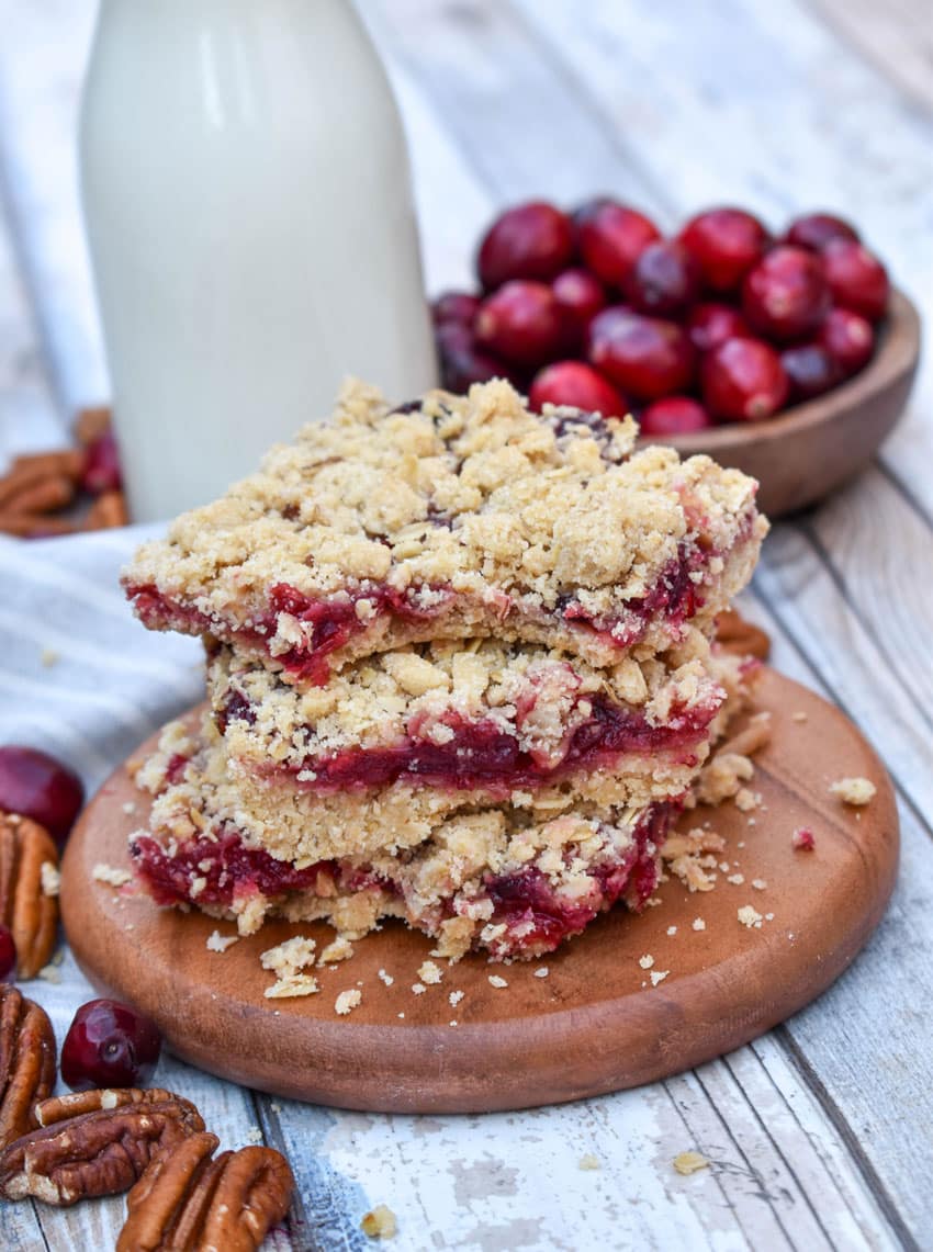 a stack of cranberry crumble bars on a small wooden serving board