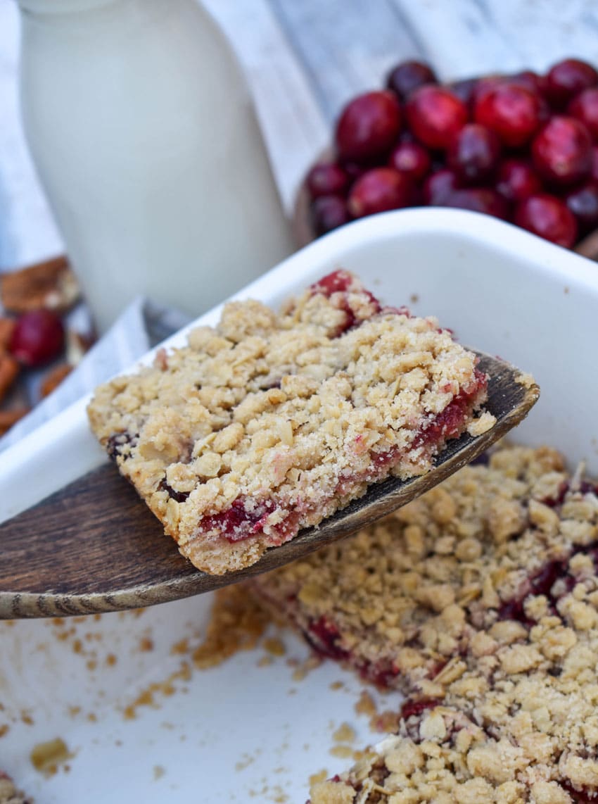 a wooden spatula holding up a sliced cranberry crumble bar