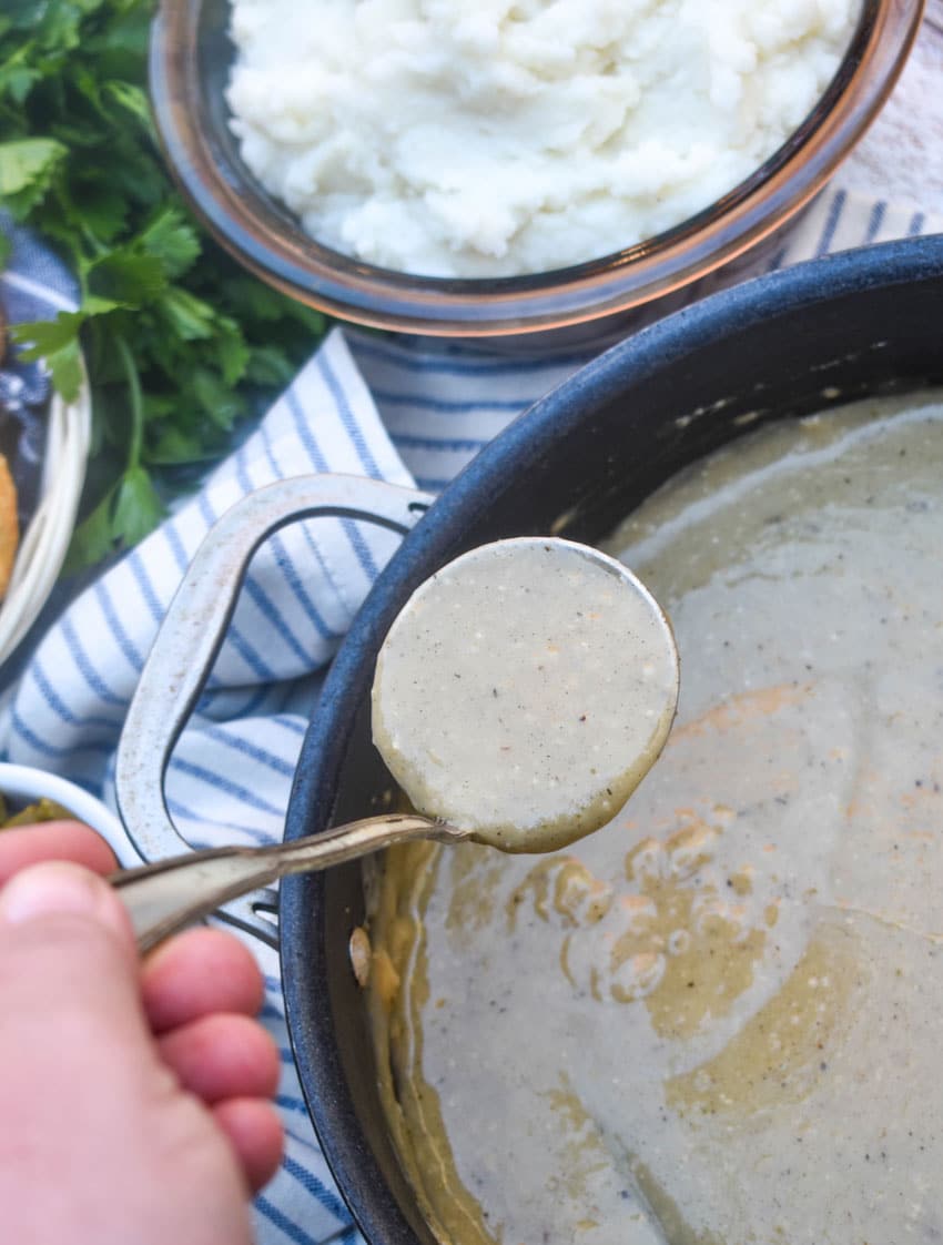 a silver ladle scooping easy chicken gravy made from scratch in a black skillet