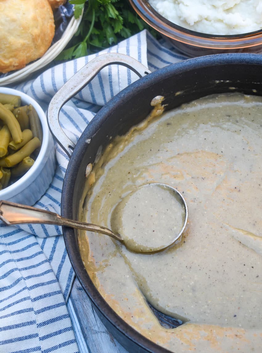 a silver ladle scooping easy chicken gravy made from scratch in a black skillet