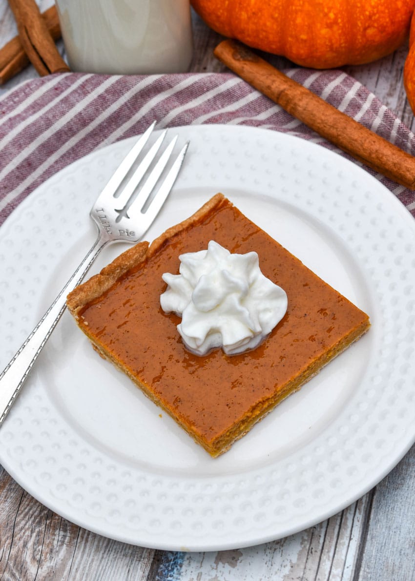 a slice of pumpkin slab pie topped with whipped cream on a small white plate