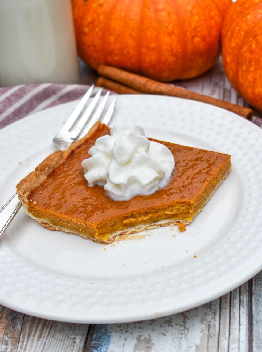 a slice of pumpkin slab pie topped with whipped cream on a small white plate