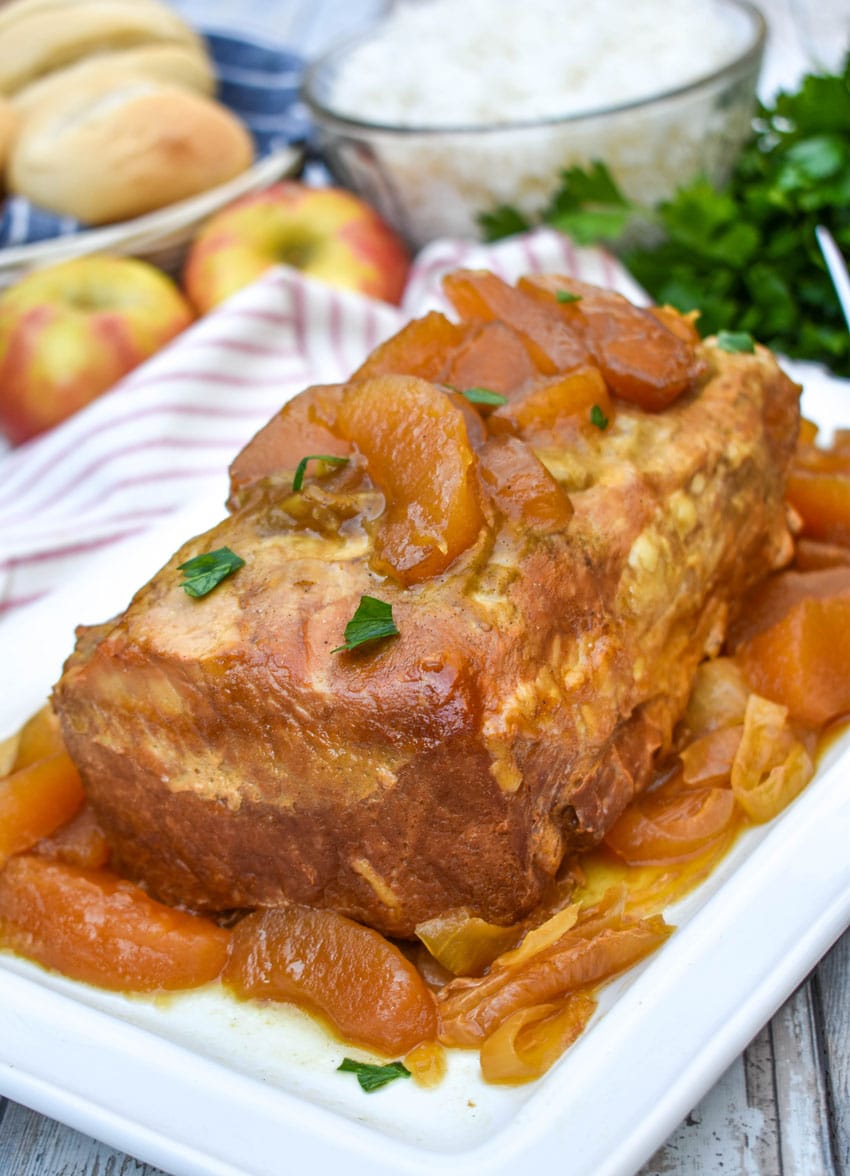 a slow cooked apple pie pork loin on a white serving platter